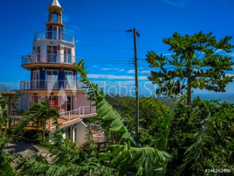 Bild på Roatan Honduras Lighthouse building Landscape of the island with a blue sky and green vegetation in the background